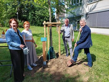 Bürgermeister und Kollegen pflanzen mit und für Awerd Riemenschneider (r.) einen Baum auf dem Schulgelände.